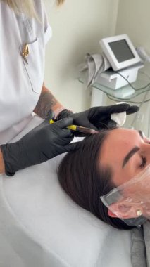 Estetik tıp: Siyah eldivenli kozmetik uzmanı tarafından kadınlara kanül enjeksiyonuyla kolajen biyo-evrizasyon tedavisine yakın çekim.