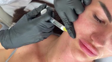 Estetik tıp: Siyah eldivenli kozmetik uzmanı tarafından kadınlara kanül enjeksiyonuyla kolajen biyo-evrizasyon tedavisine yakın çekim.