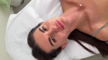 Estetikçi, genç bir kadının yüzündeki iplik kaldırma prosedüründen önce yüz hatlarını beyaz kalemle işaretliyor.