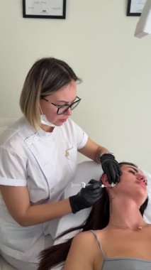 Estetik tıp: Siyah eldivenli kozmetik uzmanı tarafından kadınlara kanül enjeksiyonuyla kolajen biyo-evrizasyon tedavisine yakın çekim.