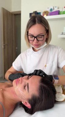 Estetik tıp: Siyah eldivenli kozmetik uzmanı tarafından kadınlara kanül enjeksiyonuyla kolajen biyo-evrizasyon tedavisine yakın çekim.