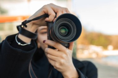 Mavi gökyüzüne karşı profesyonel bir kamera tutan bir kadın fotoğrafçının düşük açılı görüntüsü, açık hava anlarını yakalıyor ve yaratıcı fotoğrafçılığa odaklanıyor.