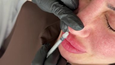 Güzellik kliniği. Eldiven giymiş güzellik uzmanları kadın derisine yüz yaşlanma enjeksiyonu yapıyor. Bir kadın güzellik yüz kozmetolojisi prosedürünü uygular. Botoks. Kolajen enjeksiyonları.