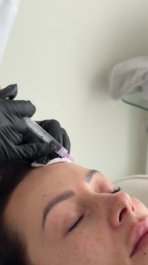Güzellik kliniği. Eldiven giymiş güzellik uzmanları kadın derisine yüz yaşlanma enjeksiyonu yapıyor. Bir kadın güzellik yüz kozmetolojisi prosedürünü uygular. Botoks. Kolajen enjeksiyonları.