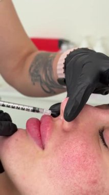 Güzellik kliniği. Eldiven giymiş güzellik uzmanları kadın derisine yüz yaşlanma enjeksiyonu yapıyor. Bir kadın güzellik yüz kozmetolojisi prosedürünü uygular. Botoks. Kolajen enjeksiyonları.