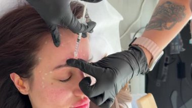 Güzellik kliniği. Eldiven giymiş güzellik uzmanları kadın derisine yüz yaşlanma enjeksiyonu yapıyor. Bir kadın güzellik yüz kozmetolojisi prosedürünü uygular. Botoks. Kolajen enjeksiyonları.