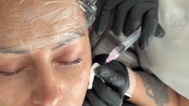 Kozmetik uzmanı, güzellik kliniğinde yaşlanma karşıtı mezoterapi prosedürü sırasında bir kadının gözü altında biyolojik evrim enjeksiyonları gerçekleştiriyor..