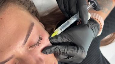 Güzellik kliniği. Eldiven giymiş güzellik uzmanları kadın derisine yüz yaşlanma enjeksiyonu yapıyor. Bir kadın güzellik yüz kozmetolojisi prosedürünü uygular. Botoks. Kolajen enjeksiyonları.