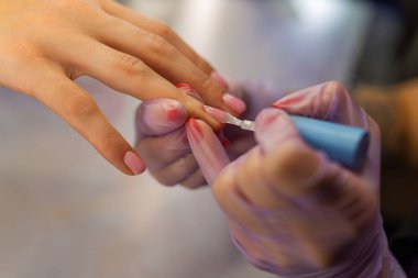Profesyonel manikür sürecini kapat. Manikürcü kadın tırnaklarına jöle sürerken güzellik salonunda koruyucu eldiven takıyor. Tırnak bakımı, hijyen, kozmetik tedavi
