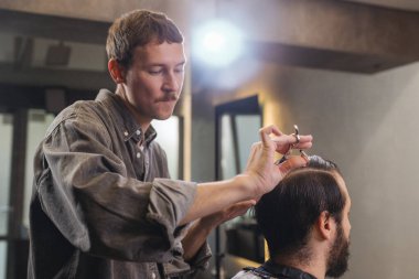 Berber, erkek müşteri saçını makas ve tarak ile kesiyor. Profesyonel saç kesim süreci, hassasiyet tekniği, modern berber dükkanında erkek bakımı.