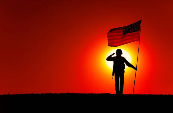 Soldado dos EUA com bandeira saudando no horizonte do pôr do sol — Fotografia de Stock