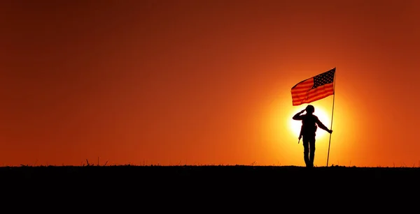 Soldado dos EUA com bandeira saudando no horizonte do pôr do sol — Fotografia de Stock