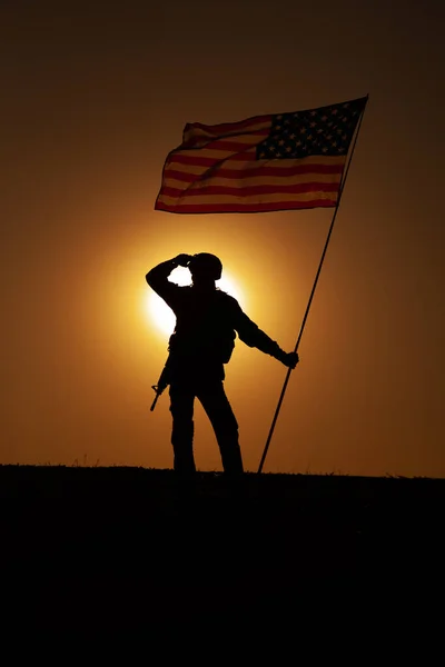 Amerikaanse soldaat met vlag ver weg kijkend bij zonsondergang — Stockfoto