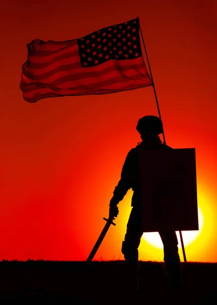 日没を背景に米軍兵士武装剣と盾のシルエットは 米国の国旗を振って下に立っている 軍の英雄と愛国者軍の栄光と名誉兵士たちの追悼 — ストック写真