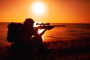 Komando nişancısı, deniz kıyısına nişan aldı, tüfeği ateşledi.