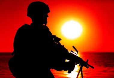 Kıyıda makineli tüfekli asker silueti