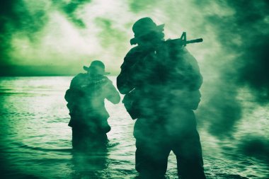 Suda yürüyen ve nişan alan komando askerleri