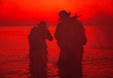 Suda yürüyen ve nişan alan komando askerleri