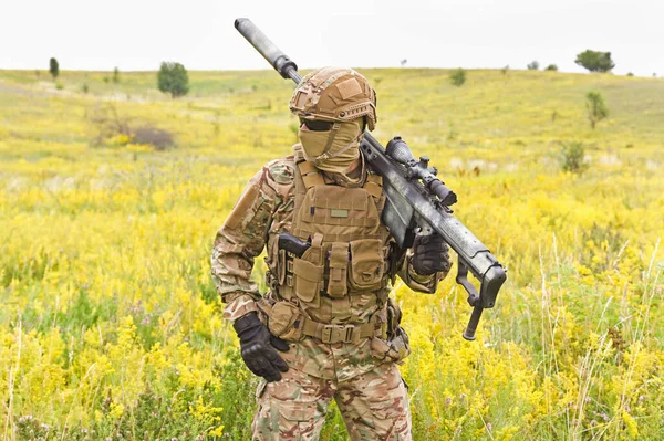 Soldado num uniforme militar especial com espingarda de atirador no terreno — Fotografia de Stock