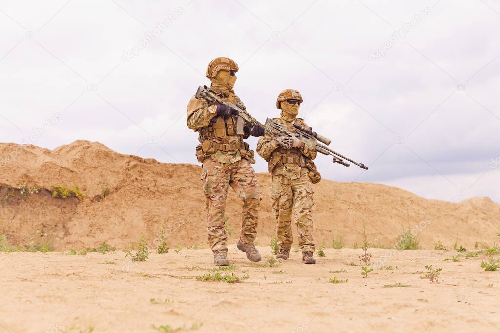 Two soldiers with rifles in the desert