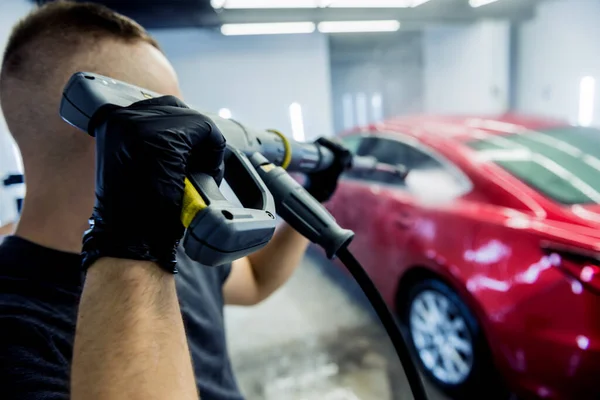 Worker washing car with high pressure water at a car wash. — Stock Photo, Image