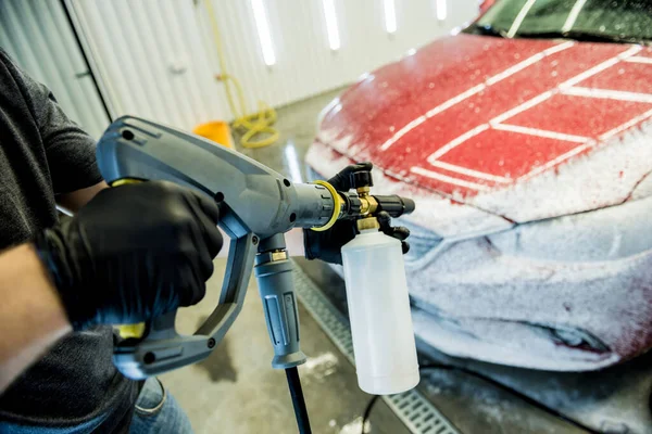 Robotnik myjący samochód z wysokim ciśnieniem wody w myjni samochodowej. — Zdjęcie stockowe