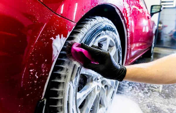 Limpieza de la rueda del coche con un cepillo y agua — Foto de Stock