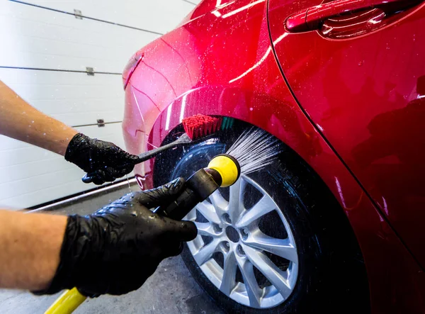 Limpieza de la rueda del coche con un cepillo y agua — Foto de Stock