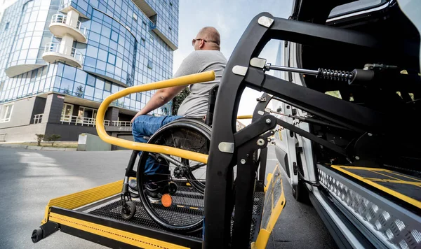 Un uomo sulla sedia a rotelle su un ascensore di un veicolo per disabili — Foto Stock
