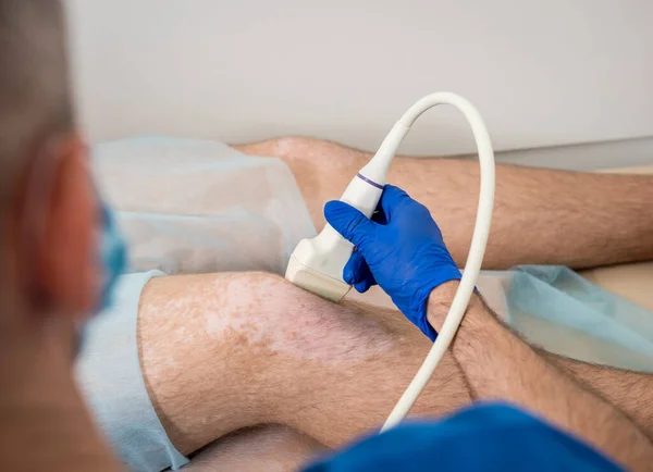 Médico haciendo un ultrasonido de la rodilla del hombre. — Foto de Stock