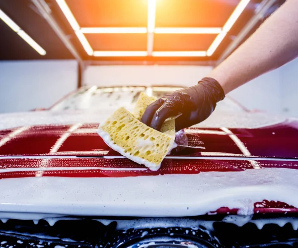 Trabalhador lavar carro vermelho com esponja em uma lavagem de carro — Fotografia de Stock