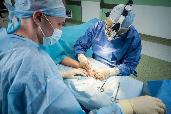 Surgeons in the operating room trying to save the patients hand.