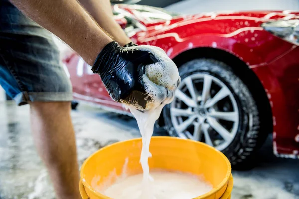 Worker washing red car with sponge on a car wash — Stock Photo, Image