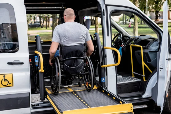 Un uomo sulla sedia a rotelle su un ascensore di un veicolo per disabili — Foto Stock