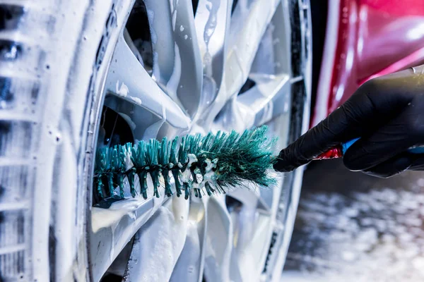 Limpieza de la rueda del coche con un cepillo y agua — Foto de Stock