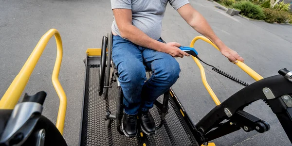 A man in a wheelchair on a lift of a vehicle for people with disabilities — Stock Photo, Image