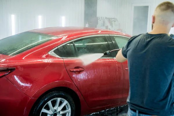 Trabajador de lavado de coches con agua de alta presión en un lavado de coches. — Foto de Stock