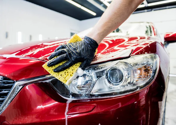 Trabajador lavando coche rojo con esponja en un lavado de coche — Foto de Stock