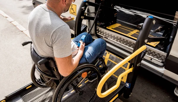 Un uomo sulla sedia a rotelle su un ascensore di un veicolo per disabili — Foto Stock