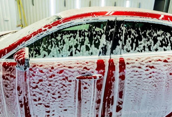 Lavado de coche rojo con espuma activa en el servicio de lavado de coches. — Foto de Stock