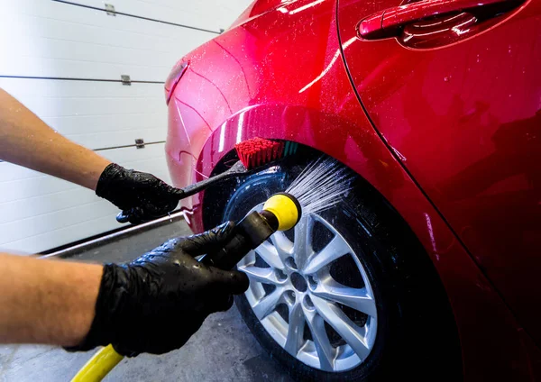 Limpieza de la rueda del coche con un cepillo y agua — Foto de Stock