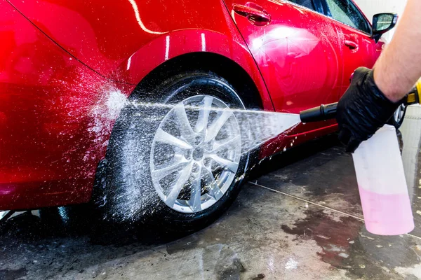 Limpieza de la rueda del coche con un cepillo y agua — Foto de Stock