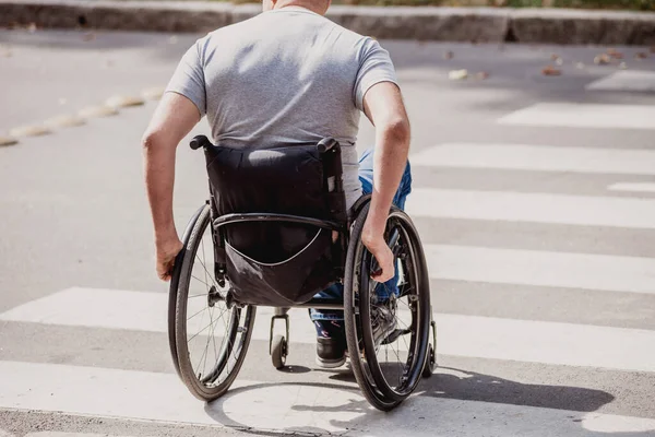 Hombre discapacitado en silla de ruedas cruzando calle carretera — Foto de Stock