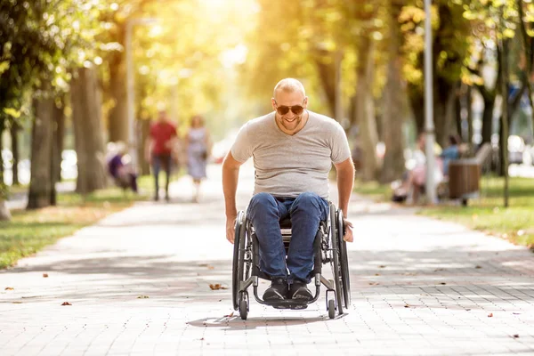 Hombre discapacitado en silla de ruedas caminar en el callejón del parque —  Fotos de Stock