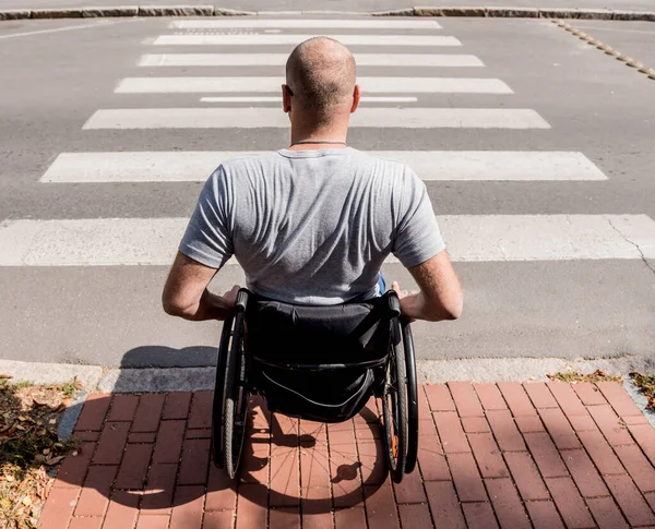 Gehandicapte man in een rolstoel maakt zich op om de weg over te steken op een voetgangersoversteek — Stockfoto