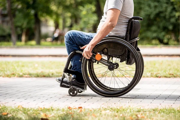 Hombre discapacitado en silla de ruedas caminar en el callejón del parque — Foto de Stock