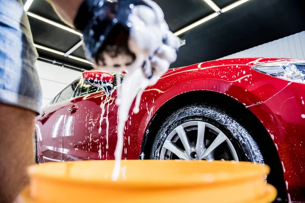 Trabajador lavando coche rojo con esponja en un lavado de coche — Foto de Stock