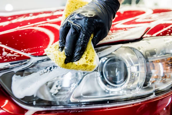 İşçi araba yıkamada kırmızı arabayı süngerle yıkıyor. — Stok fotoğraf