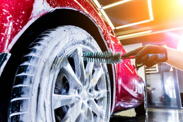 Limpieza de la rueda del coche con un cepillo y agua — Foto de Stock