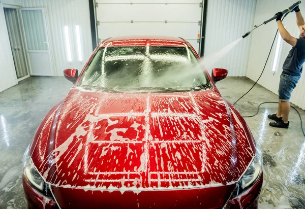 Trabajador de lavado de coches con agua de alta presión en un lavado de coches. — Foto de Stock